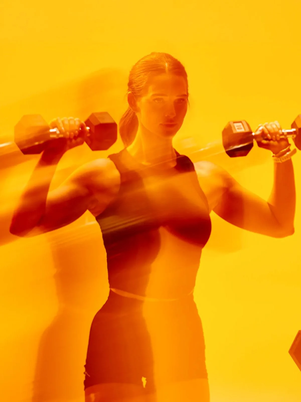 Atleta sosteniendo dos mancuernas a la altura de los hombros