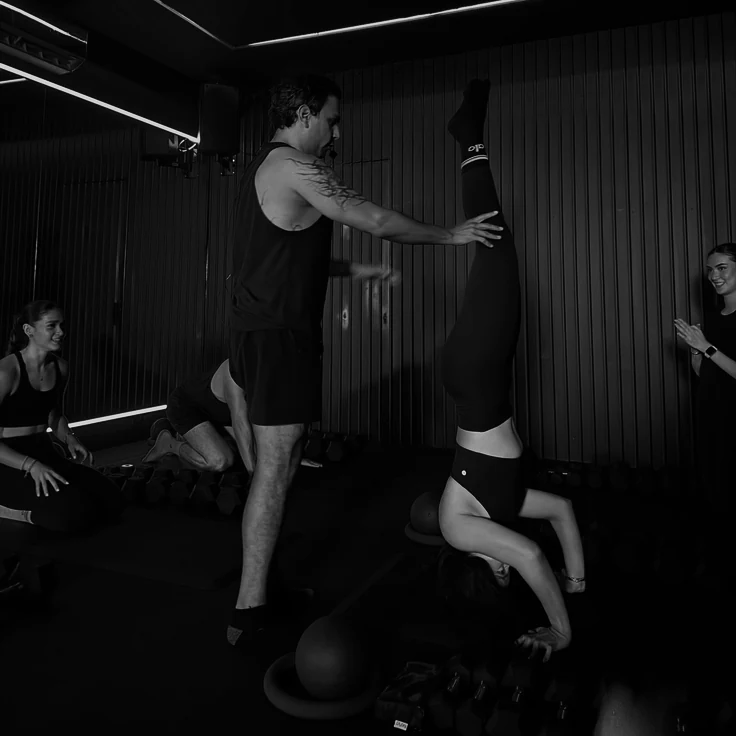 Coach spotting a student in a supported headstand during a yoga class